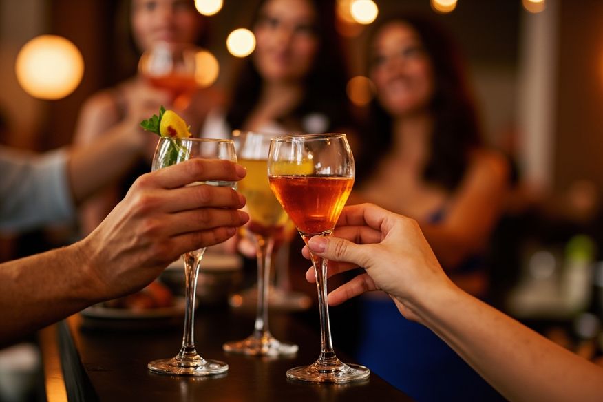 Amigos brindam com coquetéis coloridos em balcão de bar durante festa adulta