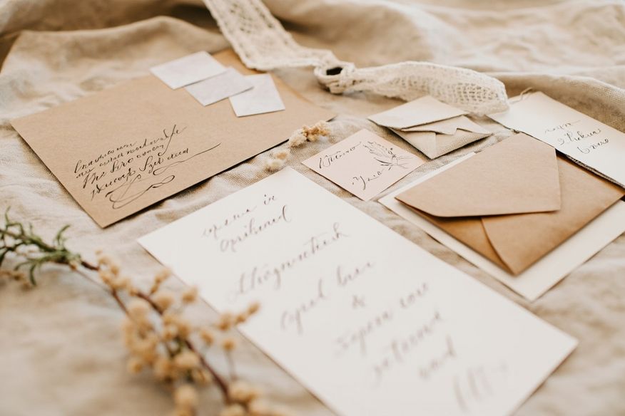 Kit de papelaria artesanal para casamento com convites em papel kraft, caligrafia manual, flores secas e barbante sobre tecido de linho