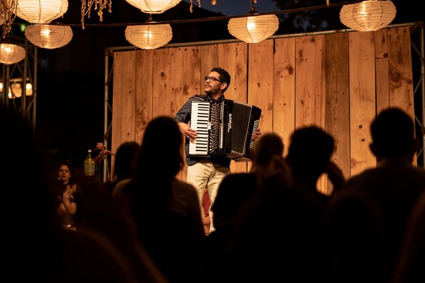 Sanfoneiro tocando em palco decorado com lanternas em Festa Junina