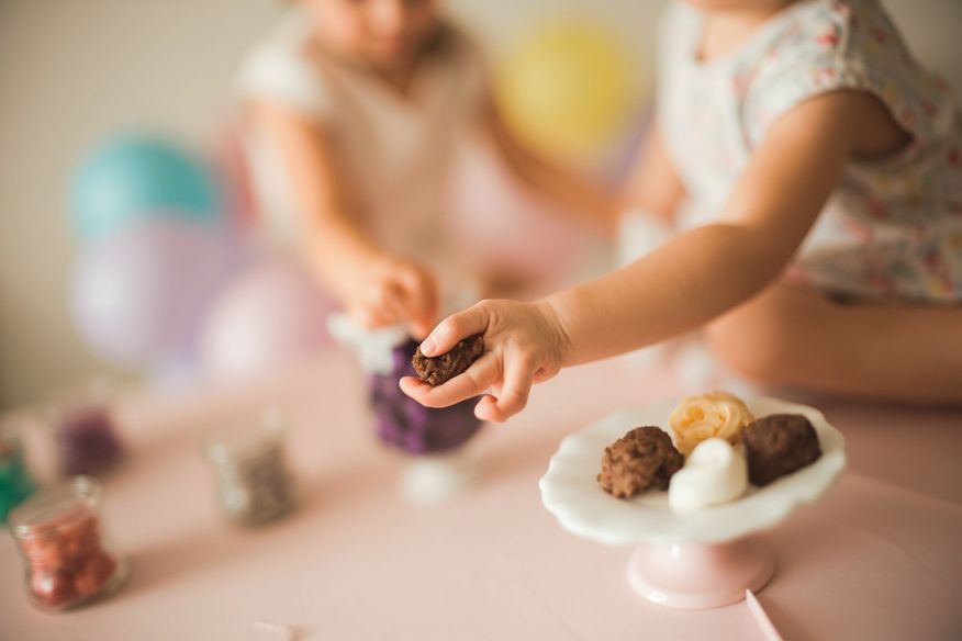 Criança pegando brigadeiro em mesa de doces decorada com balões
