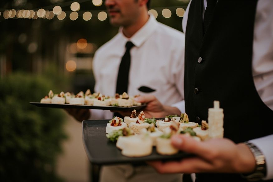 Garçom servindo hors d'oeuvres em bandeja em recepção de casamento ao ar livre ao entardecer